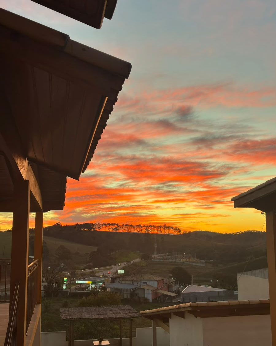 Pôr do sol visto do chalé, com o céu laranja sobre a serra de Cunha